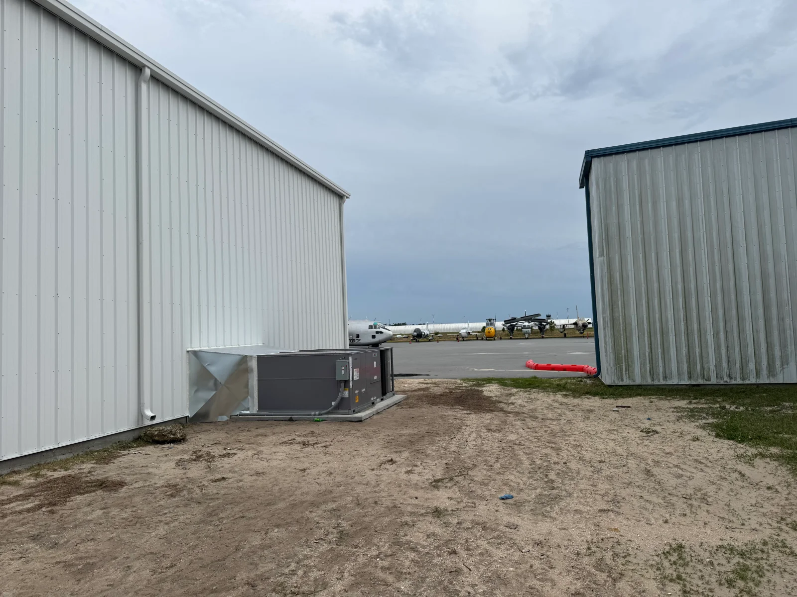 Commercial HVAC unit installed between metal buildings with ductwork and metal framework