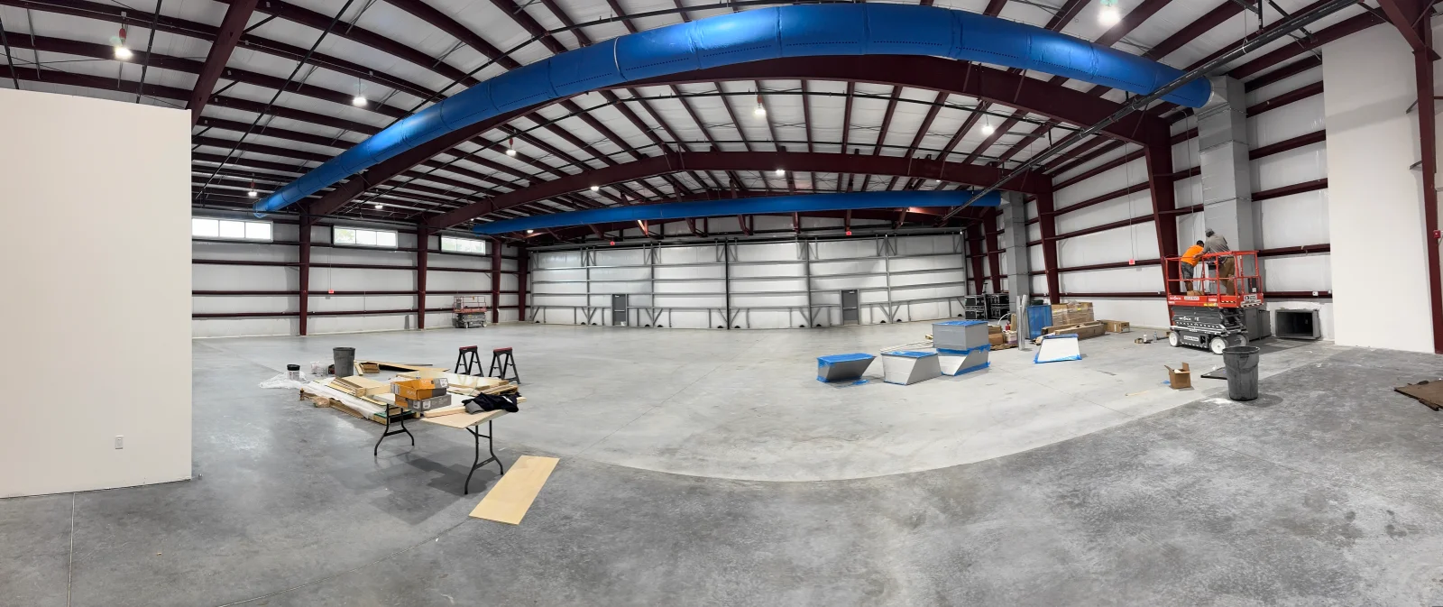 Blue HVAC ductwork installed in commercial warehouse with metal frame and concrete floor